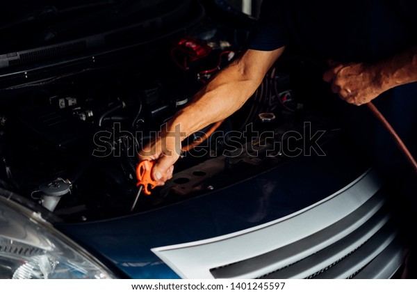 Car mechanic or serviceman cleaning the car engine\
after checking a car engine for fix and repair problem at car\
garage or repair shop
