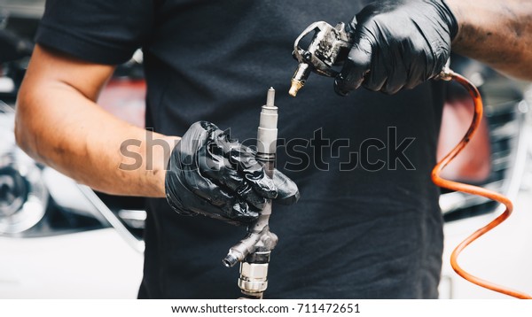 Car mechanic or\
serviceman disassembled car dirty engine for cleaning fuel\
injection and air flow system engine parts for fix and repair\
problem at car garage or repair\
shop