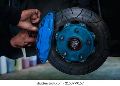 Car mechanic or serviceman disassembly and checking a disc brake and asbestos brake pads for fix and repair problem at car garage or repair shop - Shutterstock ID 2153999157