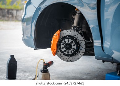 Car mechanic or serviceman disassembly and checking a disc brake and asbestos brake pads for fix and repair problem at car garage or repair shop - Powered by Shutterstock