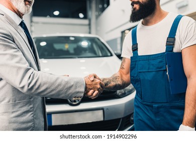 Car mechanic shakinh hands with senior business man costumer. Technical car inspection station.