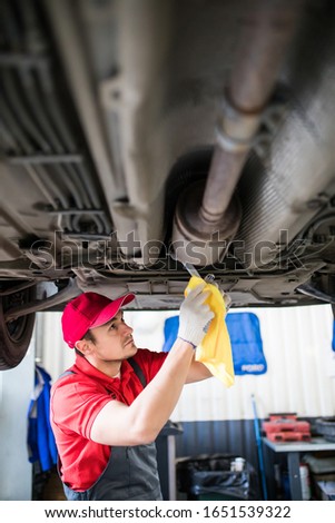 car mechanic with spanner tighten car suspension detail of lifted automobile at repair station