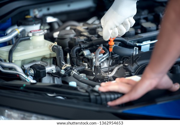 The car mechanic\
staff is pulling the oil level gauge up to check the oil level. To\
check the car condition