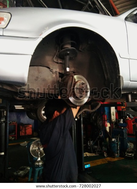 Car mechanic\
standing under car engine\
\
