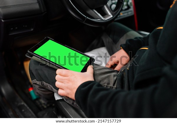 Car mechanic with tablet doing\
diagnostics detecting malfunction. Modern car rapair\
shop