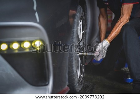 Car mechanic tightening wheel lug nuts by using Torque Wrench.