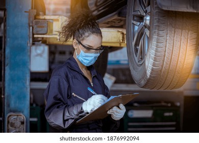 Car mechanic under checking car wheels at garage for maintenance or charge a new new wheel ,they wearing safety uniform, glasses and face mask to work.  - Powered by Shutterstock