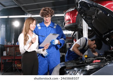 Car mechanic in uniform are checking car with asian woman customer in auto service with lifted vehicle to a. Caucasian service maintenance handsome man working under car condition on lifter.  - Powered by Shutterstock