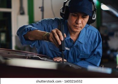 Car Mechanic In Uniform Using Ultrasonic Sound Tool To Check Irrecgular Engine Working Part At Garage And Service Station