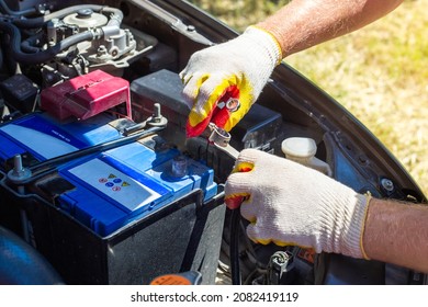 The car mechanic unscrews the car battery holder to repair or replace it. Transport service.
