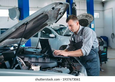car mechanic using a computer laptop to diagnosing and checking up on car engines parts for fixing and repair - Shutterstock ID 1937673061