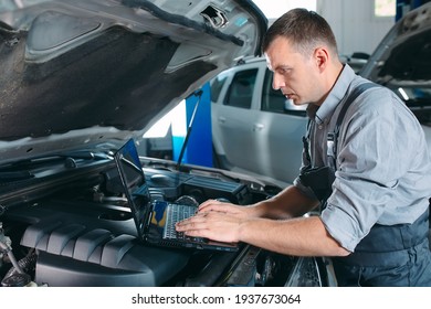 Car Mechanic Using A Computer Laptop To Diagnosing And Checking Up On Car Engines Parts For Fixing And Repair