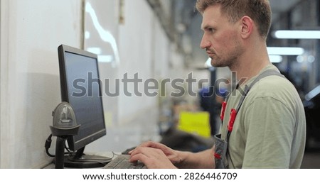 Car mechanic using computer to run diagnostic software for troubleshooting engine problems, modern computerised automotive repair.