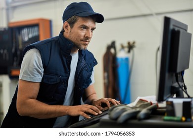 Car Mechanic Using Computer While Working In Auto Repair Shop. 