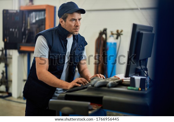 Car mechanic using computer while working at auto repair\
shop. 
