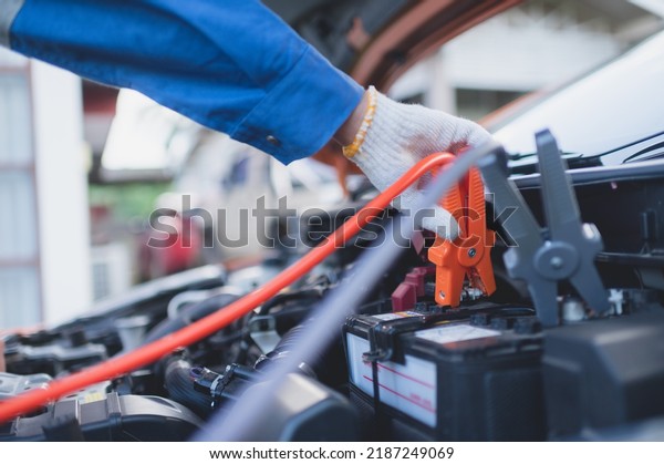 A car mechanic is using an electrical\
accumulator to test the vehicle\'s\
charge.