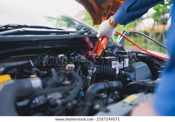 A car mechanic is using an electrical\
accumulator to test the vehicle\'s\
charge.