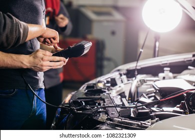 Car Mechanic Using Electrical Tool For Testing Car System In Garage Repair