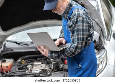 Car Mechanic Using Laptop For Checking Car Engine