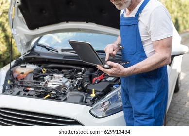 Car mechanic using laptop for checking car engine - Shutterstock ID 629913434