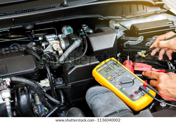 Car\
mechanic is using a multimeter with voltage range measurement to\
check the voltage level of the car\
battery.\
