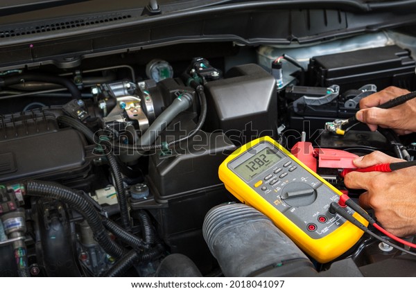 Car\
mechanic is using a multimeter with voltage range measurement to\
check the voltage level of the car\
battery.	