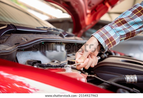 Car mechanic using small wrench\
to repair battery the car in front of the house. A new service that\
can call a technician to repair at home. Technician\
garage