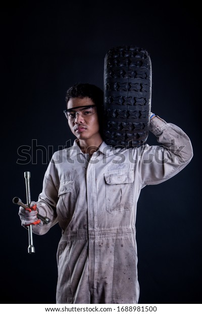 Car mechanic wearing a\
white uniform stand holding wrench isolated on gray background with\
copy space.