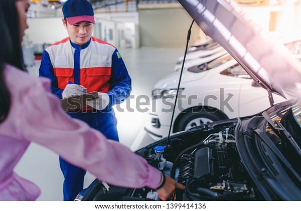 A car mechanic\
and a woman customer is asking for a problem to repair the car of a\
girl in a car repair shop.