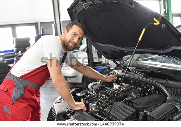 car mechanic in work clothes works in a workshop and\
repairs a vehicle 