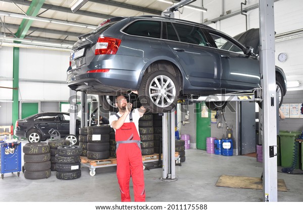 car mechanic in work clothes works in a workshop and
repairs a vehicle 