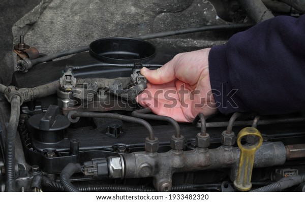 Car\
mechanic worker fixing modern common rail diesel engine, closeup of\
hand placing electrical connector to\
injector