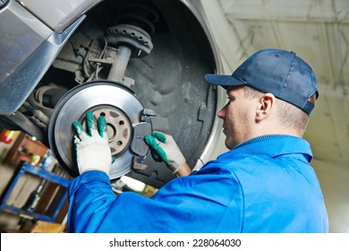 Car Mechanic Worker Replacing Brakes Of Lifted Automobile At Auto Repair Garage Shop Station