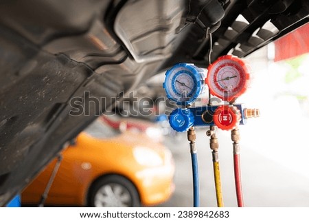 Car mechanic working in auto repair shop, inspecting the operation of the car's air conditioner and refrigerant.