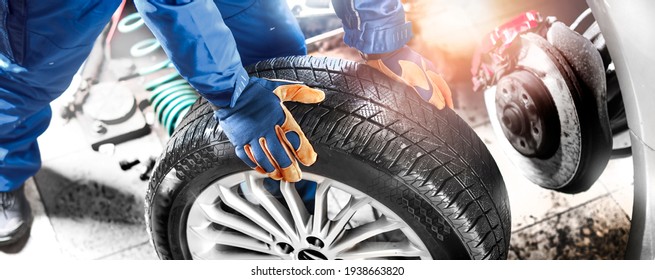 Car Mechanic Working In Garage And Changing Wheel Alloy Tire. Repair Or Maintenance Auto Service. Wide Banner, Panorama Photo.