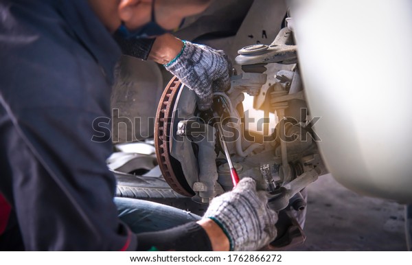 A car mechanic working grinding brake disc with\
grinding machine and vehicle brake disc turning for disc brake\
system repair car safety.
