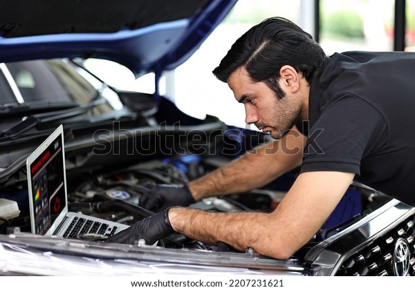 Car mechanic working with a notebook in Auto\
Repair Service checking car\
engine.
