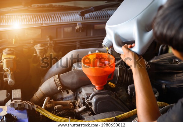 Car mechanic working in a car repair shop\
Pour the engine oil to change the engine oil in the garage for\
customers who use it Car repair and oil\
change