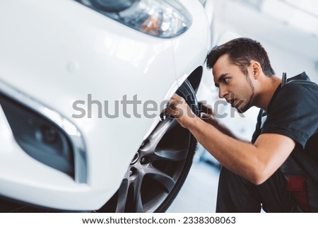 Car mechanic working in workshop checking tyre on wheel. Service station