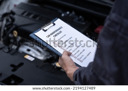 Car mechanical engineering doing checklist to estimate repair quotation to client at workshop garage.