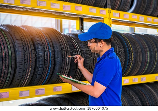 Car Mechanics check\
quality tire of car wheels in store warehouse for customer in\
garage ,car service.  