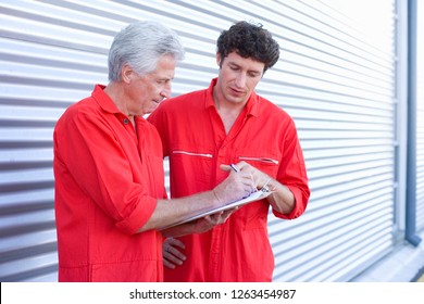 Car Mechanics In Overalls By Door Of Auto Repair Garage