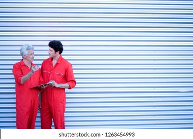 Car Mechanics In Overalls By Door Of Auto Repair Garage