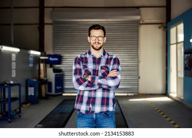 A Car Mechanic's Workshop Owner Smiling At The Camera.