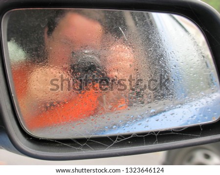 Similar – Eine Frau in einer mit großem Ausschnitt sitzt in ihrem Auto auf der rechten Seite vorne und schminkt sich, legt Schmuck an. Man kann sie durch die Reflexion in der Windschutzscheibe nicht erkennen