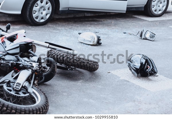 Car mirror, headlight, helmet and motorcycle\
lying on the road after a car\
crash