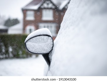 Car Mirror Parked On Drive Snowed In Heap Of Snow Settled On Top House In Background On Residential Street Whole Vehicle Covered In Blanket Of White Snowfall Frozen And Icy