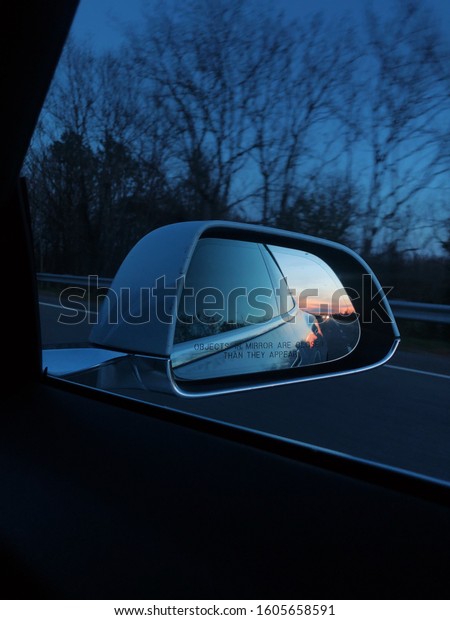A car mirror\
reflection of a beautiful\
sunset