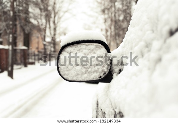 Car mirror snow capped.\
Outside.