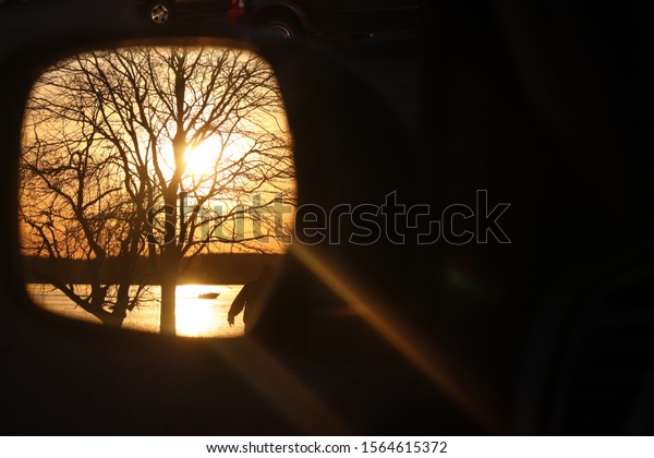 Car mirror\
sunset, over lake with a boat and\
tree